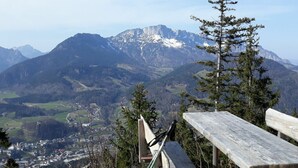A bench overlooking a mountainous landscape with a town in the valley below.