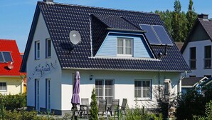 A two-story house with a sloped roof, solar panels, and a satellite dish. - Haus Kranich Modern Retreat (Glowe)