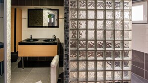 Um banheiro moderno com pia dupla, um espelho grande e um divisória de vidro decorativa.