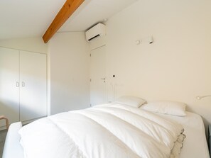 A bedroom with a bed, a wardrobe, and an air conditioning unit. - Holiday Home in Koksijde With Garden (Koksijde)