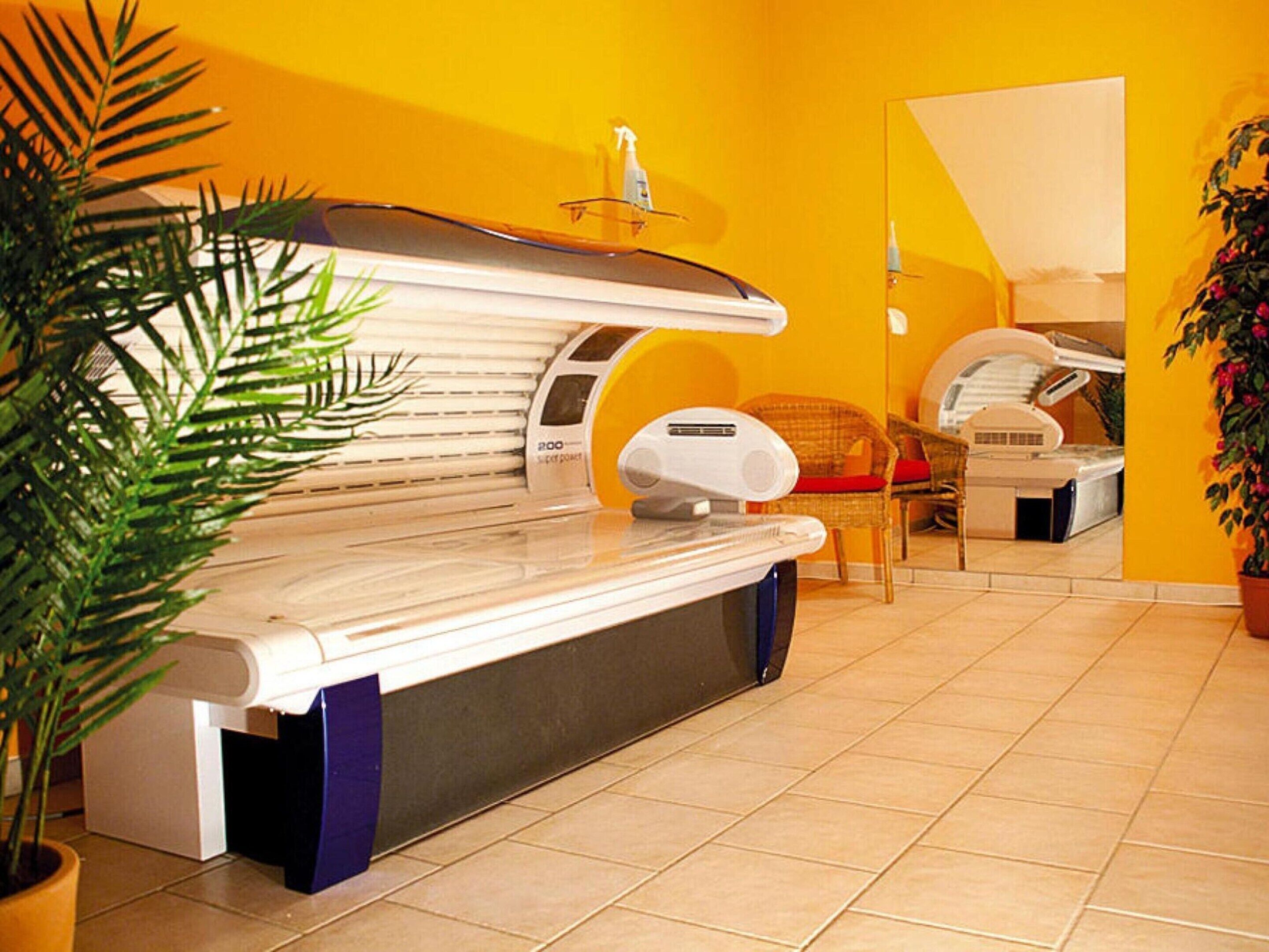 A room with a massage therapy table, a chair, and a small potted plant.