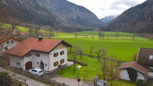 A rural house with a red-tiled roof, a white exterior, and a car parked in front. - Stay in Alpine Bayrischzell (Bayrischzell)