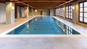 An indoor swimming pool with a wooden ceiling and large windows. - Holiday Apartment in Gerlitzen With Wellness Area (Treffen)