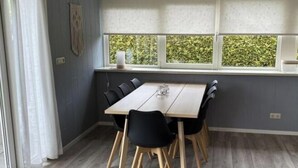 Un comedor con una mesa y sillas, una ventana con persianas, y una puerta con felpudo.