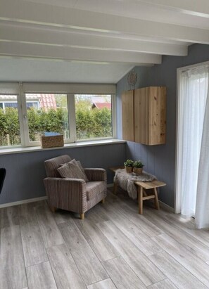 Relax in a peaceful retreat with a comfortable armchair and a view of lush greenery.