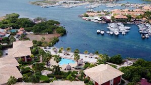 A marina with boats, a swimming pool, and resort buildings. - Holiday Home by Sea Willemstad Pool (Jan Thiel)