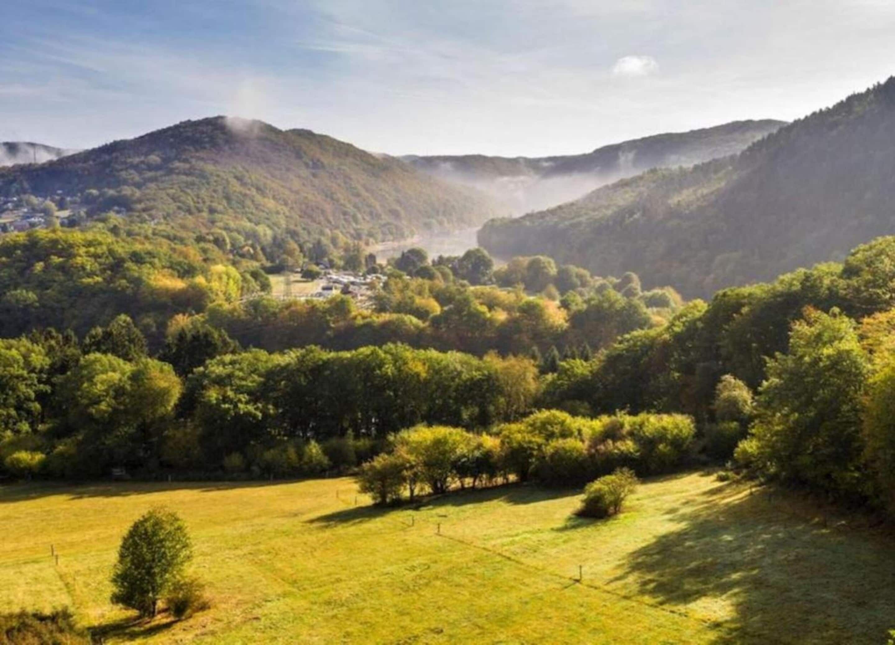 A rural landscape with rolling hills, a small village, and a clear sky.