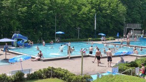 A public swimming pool with multiple lanes, a water slide, and a lifeguard stand. - Bungalow auf dem Campingpark Waxweiler (Waxweiler)