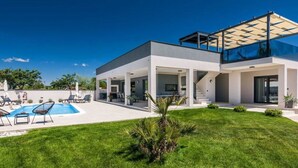 A modern two-story house with a swimming pool, outdoor seating, and a well-maintained lawn. - Villa Bella Vita (Barban)