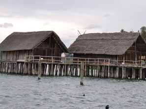 Una struttura in legno con tetti di paglia sopra l'acqua, sostenuta da palafitte.