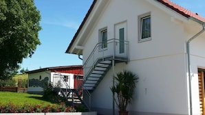 A two-story building with a red-tiled roof, a balcony, and a staircase leading to the upper floor. - Beech Modern Retreat (Ueberlingen)