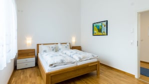 A bedroom with a wooden bed, white walls, and a painting on the wall. - Beech Modern Retreat (Ueberlingen)