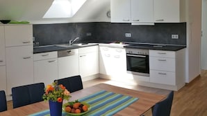 A modern kitchen with white cabinets, a black countertop, and a skylight. - Beech Modern Retreat (Ueberlingen)