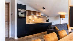 Een moderne keuken met donkere kastjes, houten aanrecht en een inbouwoven.