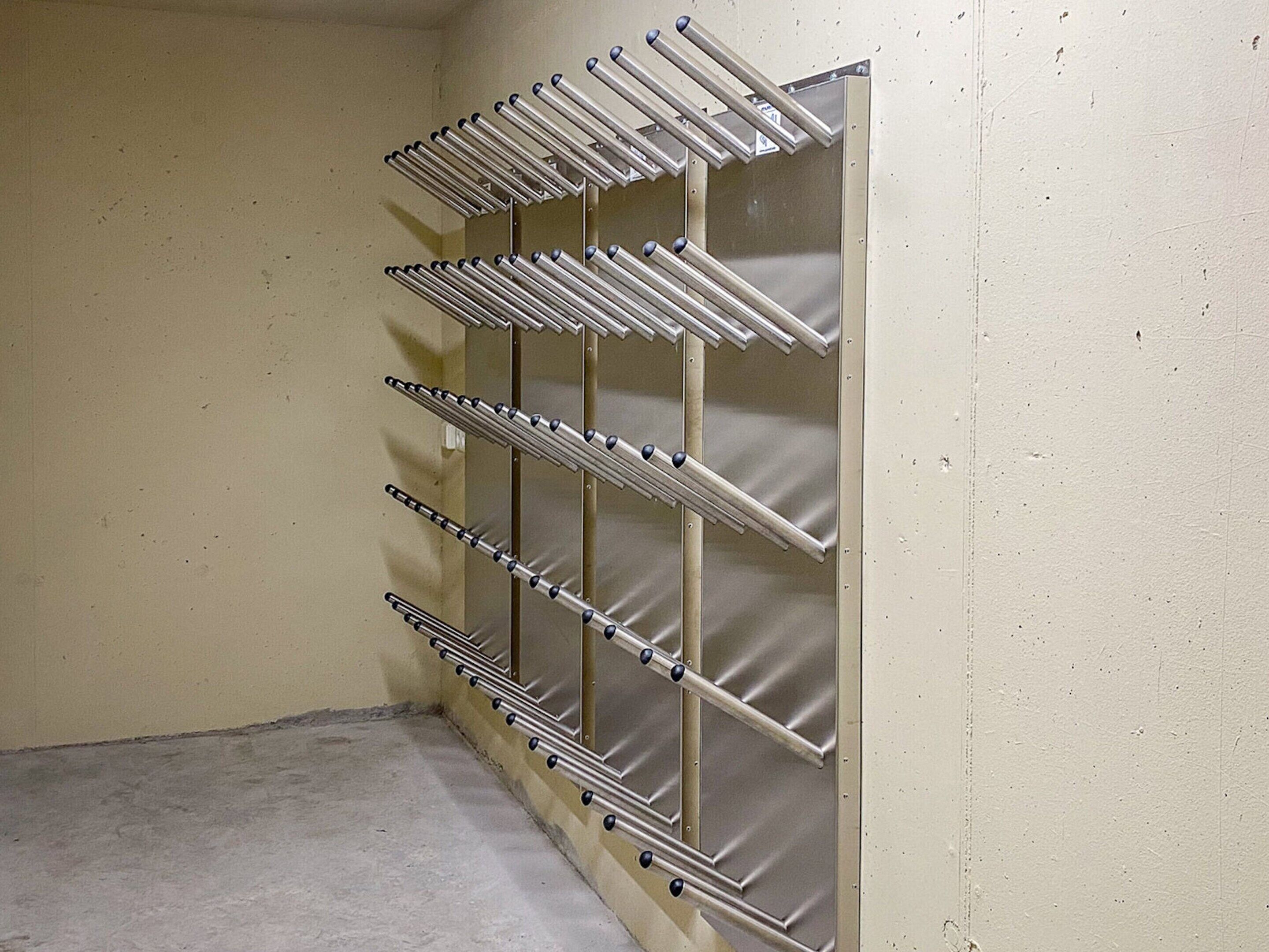 Ein Metalltrockner mit mehreren Wäscheklammern an einer Wand in einem Raum mit schlichtem Boden und Wand.