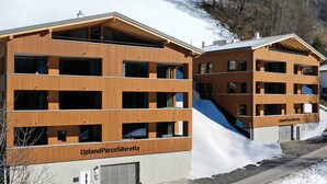 Een modern gebouw met meerdere balkons en een skipiste.