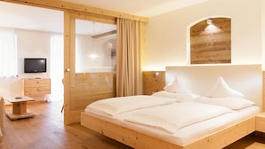 A wooden-framed bedroom with a bed, a TV, a desk, and a mirror. - Apartment Carpe Diem (Merano)