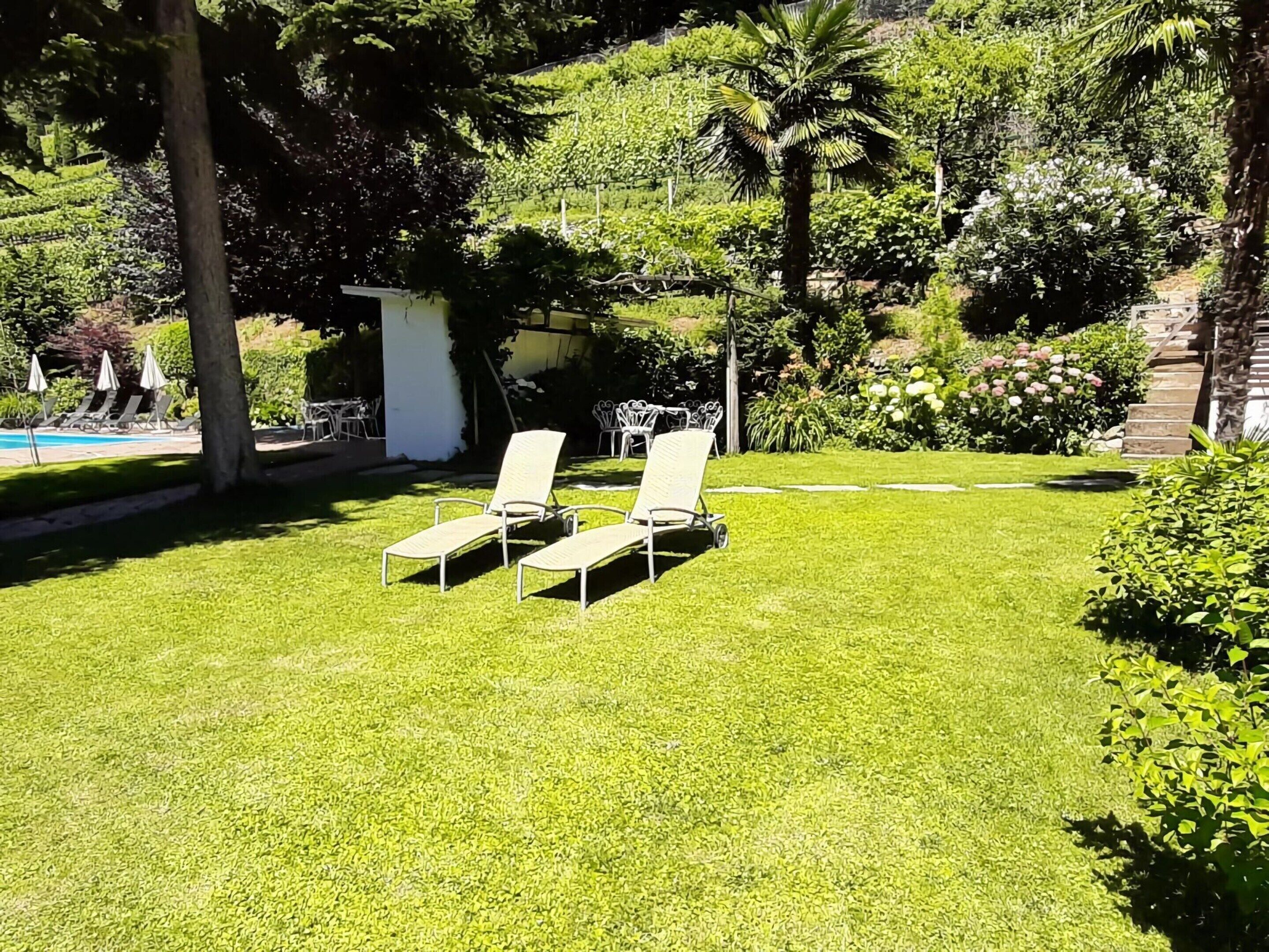 Une pelouse bien entretenue, agrémentée de deux chaises longues et d’un petit espace piscine en arrière-plan.