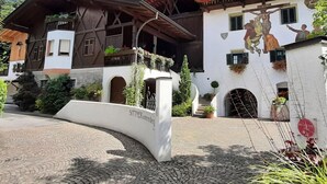 A traditional chalet with a wooden facade, a balcony with flower boxes, and a mural on the side. - Apartment Carpe Diem (Merano)