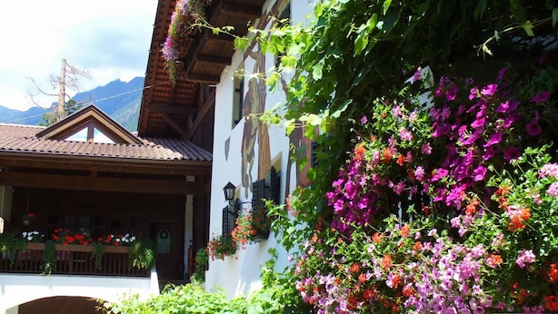 A traditional building with a balcony, a wooden roof, and a white facade. - Apartment Carpe Diem (Merano)