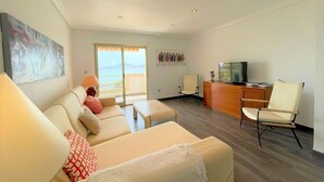 A living room with a sofa, a TV, and a desk. There is a balcony with a view. - Belvilla by OYO Villa in La Manga del mar Menor (Cartagena)