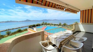 A balcony with a pool, dining table, and chairs, overlooking a beach and sea. - Belvilla by OYO Villa in La Manga del mar Menor (Cartagena)