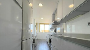 A narrow kitchen with white cabinets, a stainless steel sink, and a window providing natural light. - Belvilla by OYO Villa in La Manga del mar Menor (Cartagena)