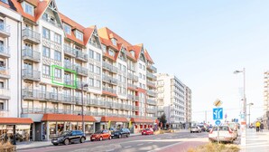 A multi-story building with balconies, a pedestrian walkway, and parked cars. - Apartment by the Coast With Sunny Terrace (Koksijde)