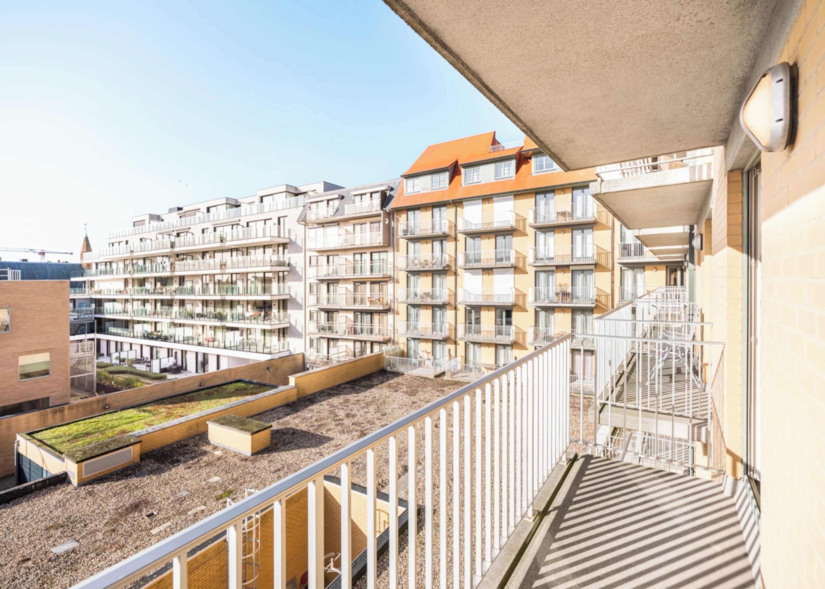 A multi-story residential building with balconies, a rooftop garden, and a staircase leading to an upper level.