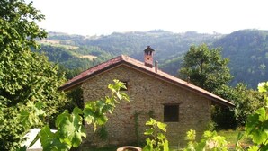 A stone building with a red roof, surrounded by lush greenery and hills in the background. - Holiday Home Cascina Lovera (Bonvicino)