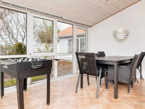 Un área de patio al aire libre con una mesa de fútbol de mesa, una mesa de comedor con sillas y una lámpara colgante.