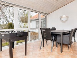 An outdoor patio area with a foosball table, a dining table with chairs, and a hanging pendant light.