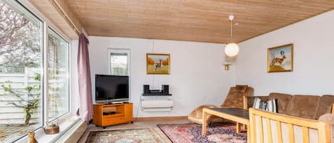 Una sala de estar con televisor, sofá y dos cuadros en la pared.