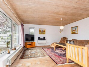 A living room with a television, sofa, and two paintings on the wall. - 9 Person Holiday Home in Thyholm (Thyholm)