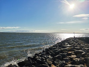 A rocky shoreline with waves, a clear sky, and the sun shining. - 9 Person Holiday Home in Thyholm (Thyholm)