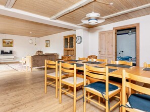 A dining area with a wooden table and chairs, a clock on the wall, and a wooden ceiling. - 9 Person Holiday Home in Thyholm (Thyholm)