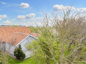 A residential property with a sloped roof, a fenced yard, and a view of the surrounding landscape.