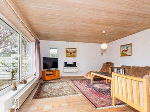 A living room with a TV, sofa, and two paintings on the wall.