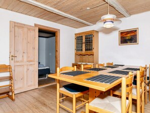 A room with a wooden dining table, chairs, a bed, and a door leading to another room. - 9 Person Holiday Home in Thyholm (Thyholm)