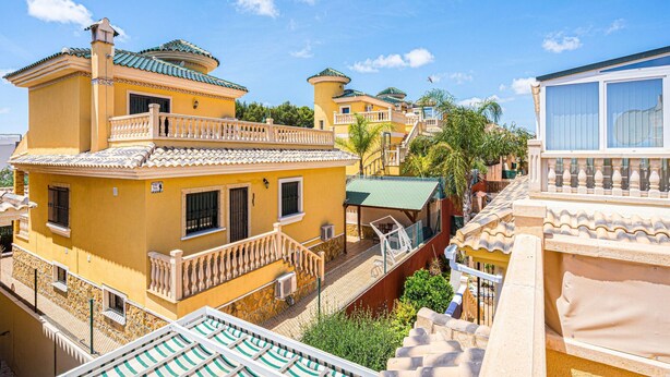Um edifício amarelo com varanda e área de piscina.