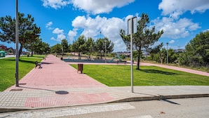 Um parque com uma passarela pavimentada, bancos e árvores.