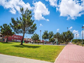 A park with a paved walkway, benches, and a playground.
