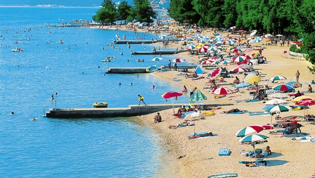 Una spiaggia affollata con molti ombrelloni e persone che si godono il mare.