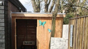 A wooden garage with a butterfly decoration and a sign reading "LEOK". - Holiday Home Leuk Comfortable Vacation Home (Callantsoog)