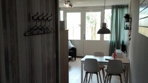 A hallway leading to a dining area with a table and chairs, wooden paneling on the walls, and a hanging light fixture. - Holiday Home Leuk Comfortable Vacation Home (Callantsoog)