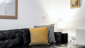 Un salon moderne avec un canapé en cuir noir, une table basse noire et une lampe.