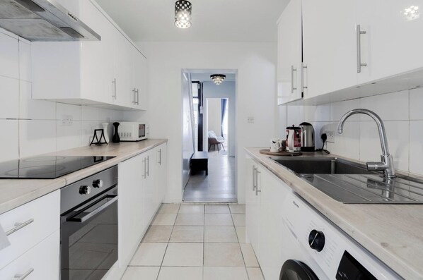 A modern kitchen with white cabinets, a stainless steel sink, and a built-in oven.