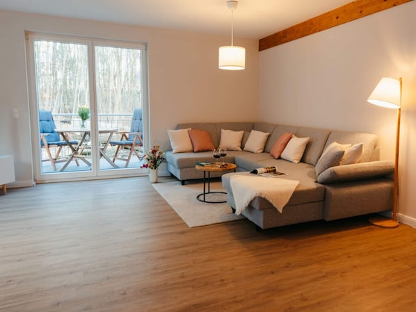 A modern living room with a sectional sofa, a coffee table, and a dining area with chairs and a table.