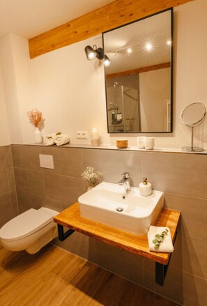 A modern bathroom with a wooden vanity, a large mirror, and a toilet.