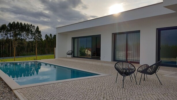 Una casa moderna con piscina, area relax esterna e ampie vetrate.